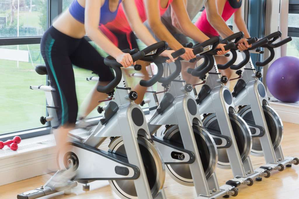 Mid section of four people working out at exercise bike class in gym