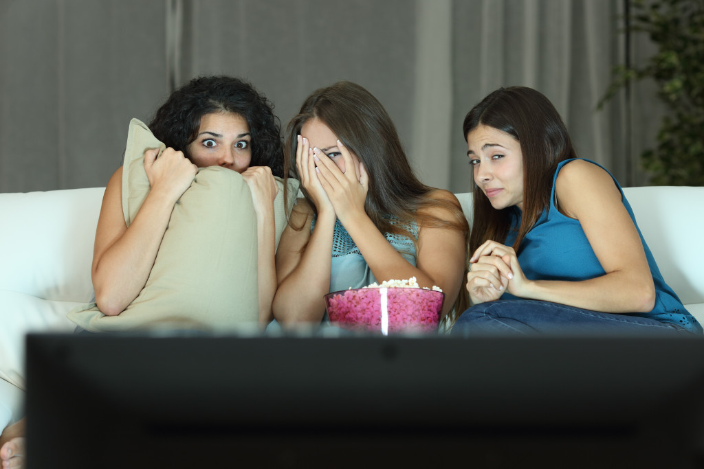 Scared girls watching a horror movie on the living room couch