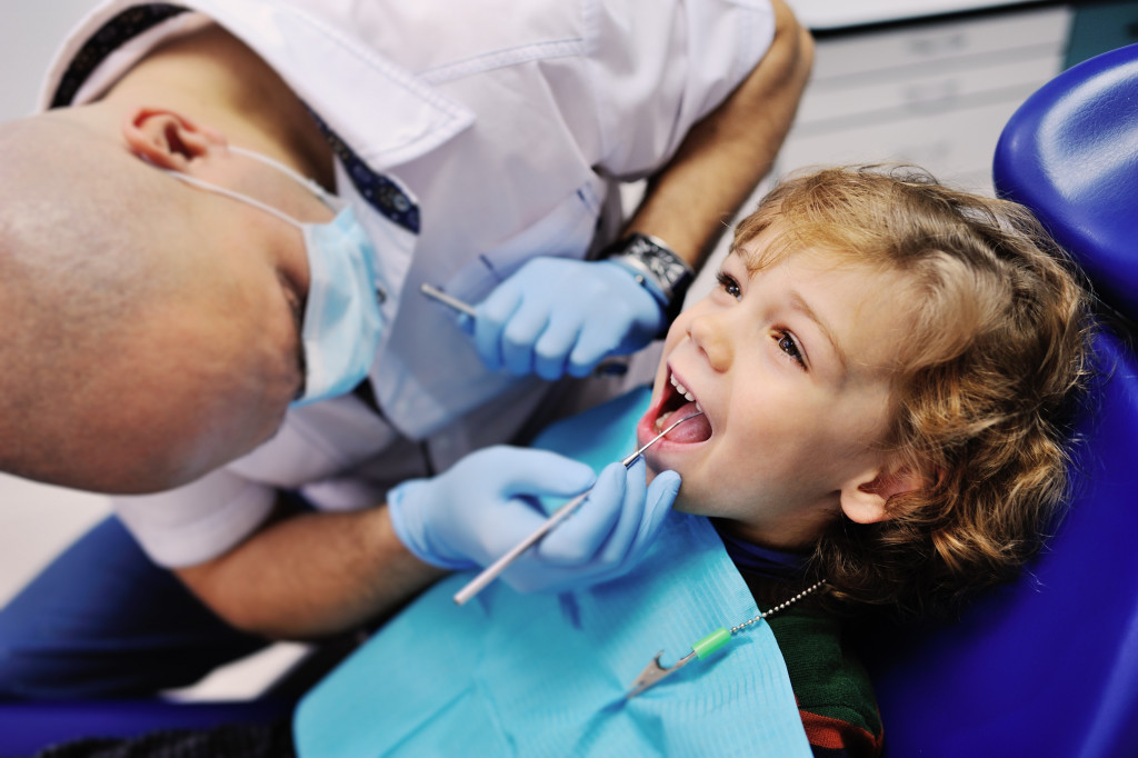 A dentist checking a young boy's mouth and teeth in the clinic