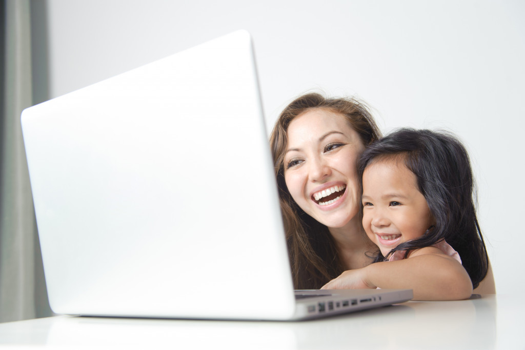 mom and daughter facing a laptop