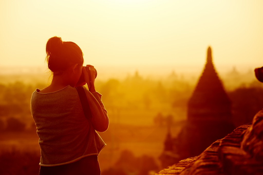 a female travel photographer taking a picture of temples at Bagan Myanmar at sunrise