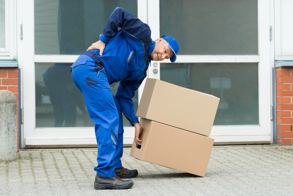 A courier having a backache due to heavy lifting