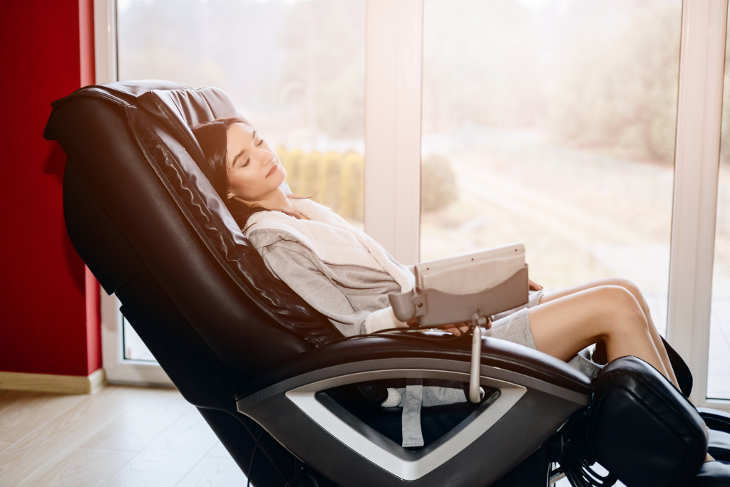 A woman relaxes on her massage chair inside her home.