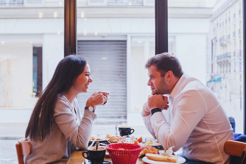 a woman and man talking at each other in a cafe
