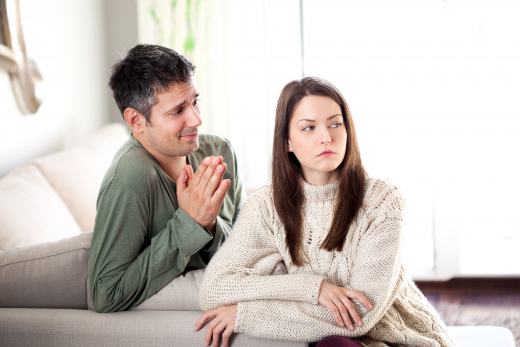 A man apologizing and begging a woman to forgive him at home