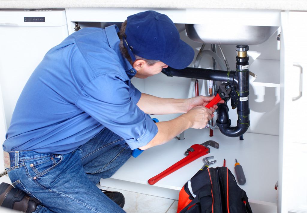 A plumber fixing a leak in the kitchen