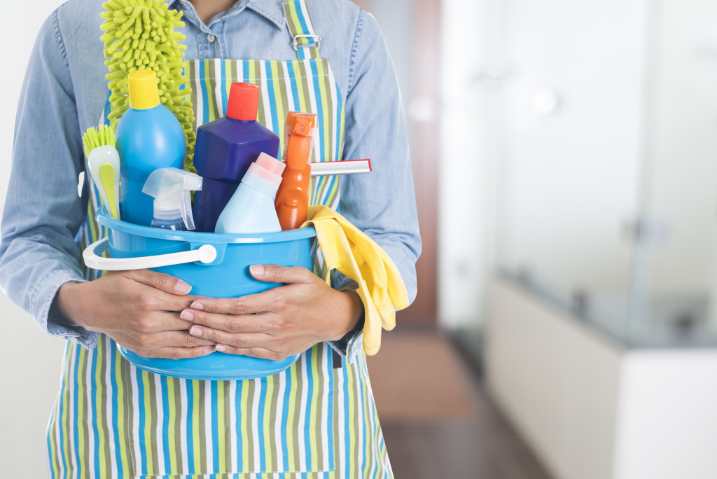 Focus on cleaner's hands holding a bucket of cleaning supplies