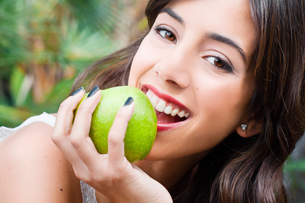 a young woman holding an apple about to take a bite