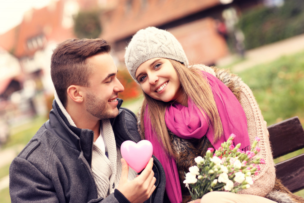 A couple on Valentine's Day in the park with flowers and heart