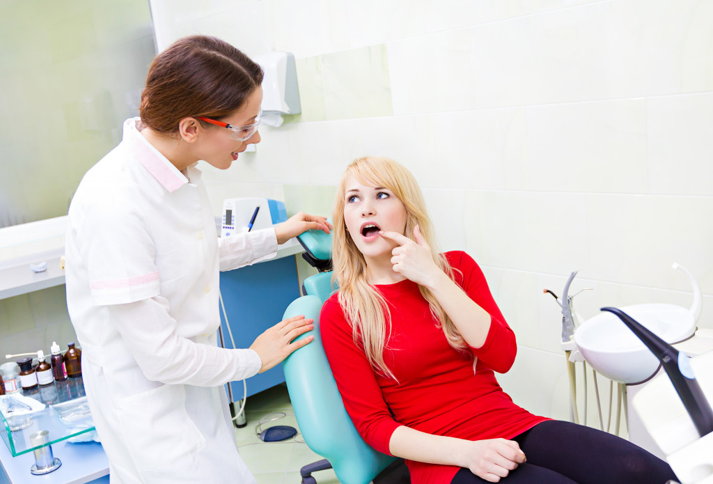 a woman pointing at tooth at the dentist