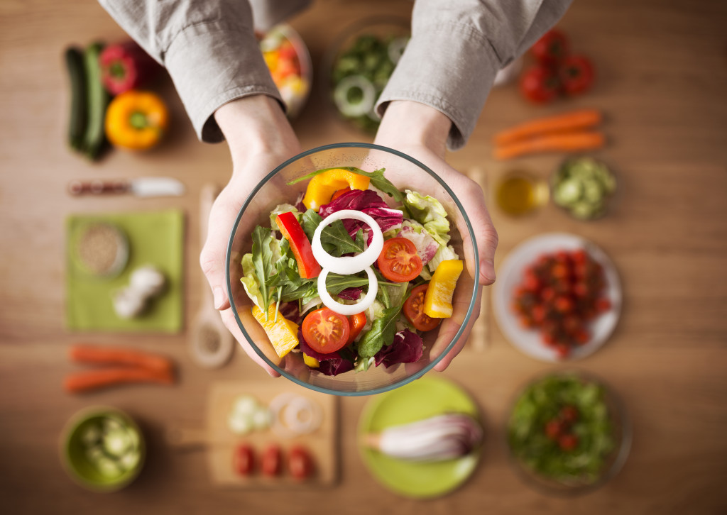 hands holding a bowl of healthy salad