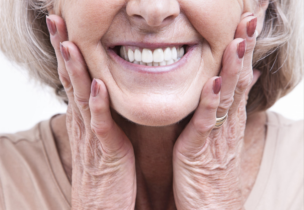 a photo of an old woman smiling with hands on her cheeks