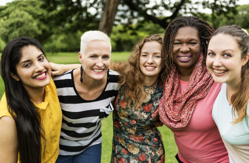 A group of interracial women happily hugging each other while outdoors