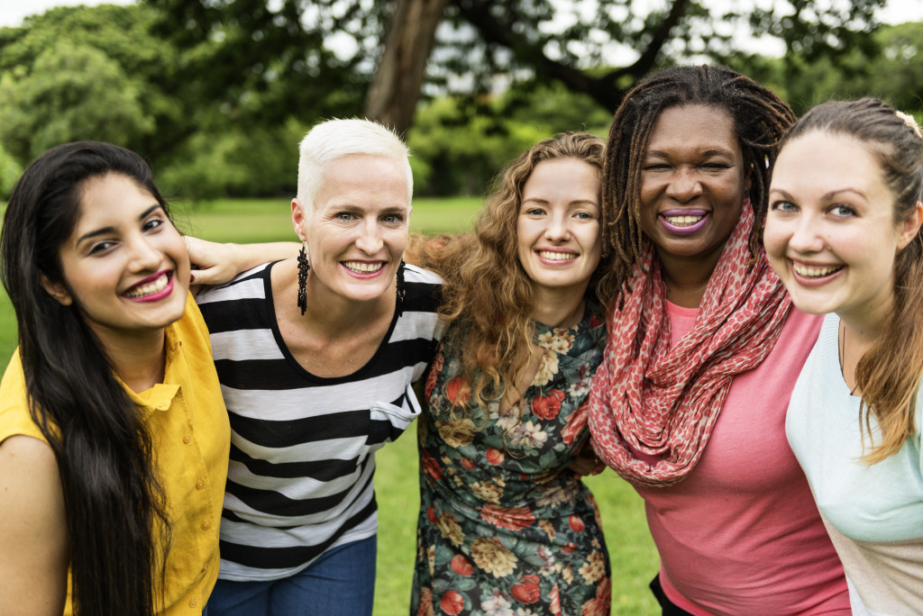 A group of interracial women happily hugging each other while outdoors