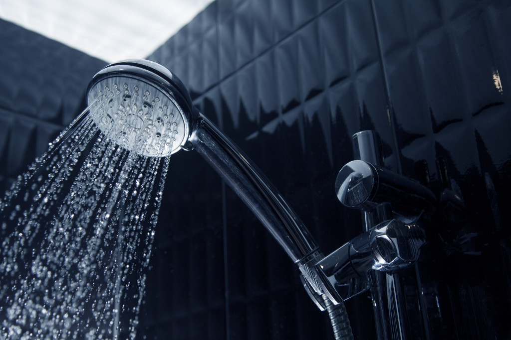 a shower head in a black-tiled bathroom