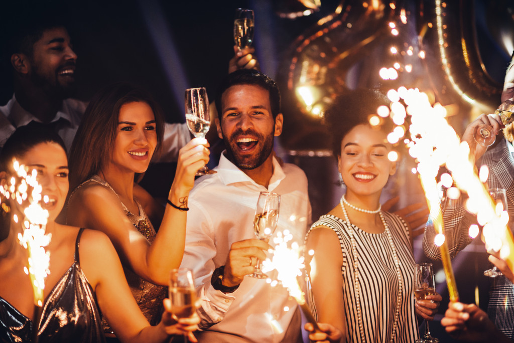 people holding glasses of alcohol and sparklers while enjoying the party