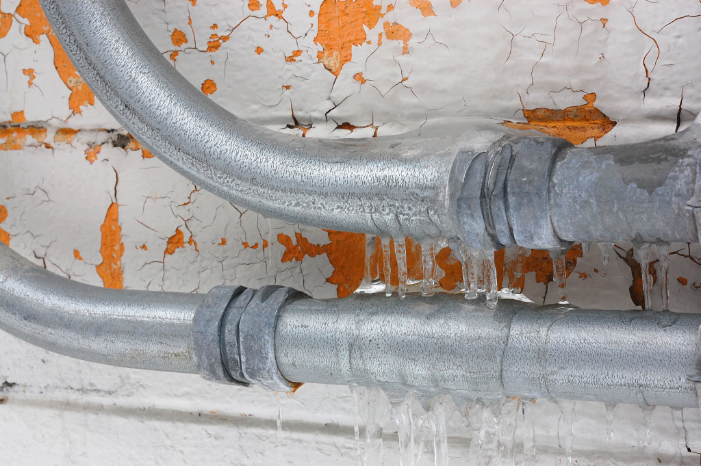 Frozen pipes in front of a wall with peeling paint
