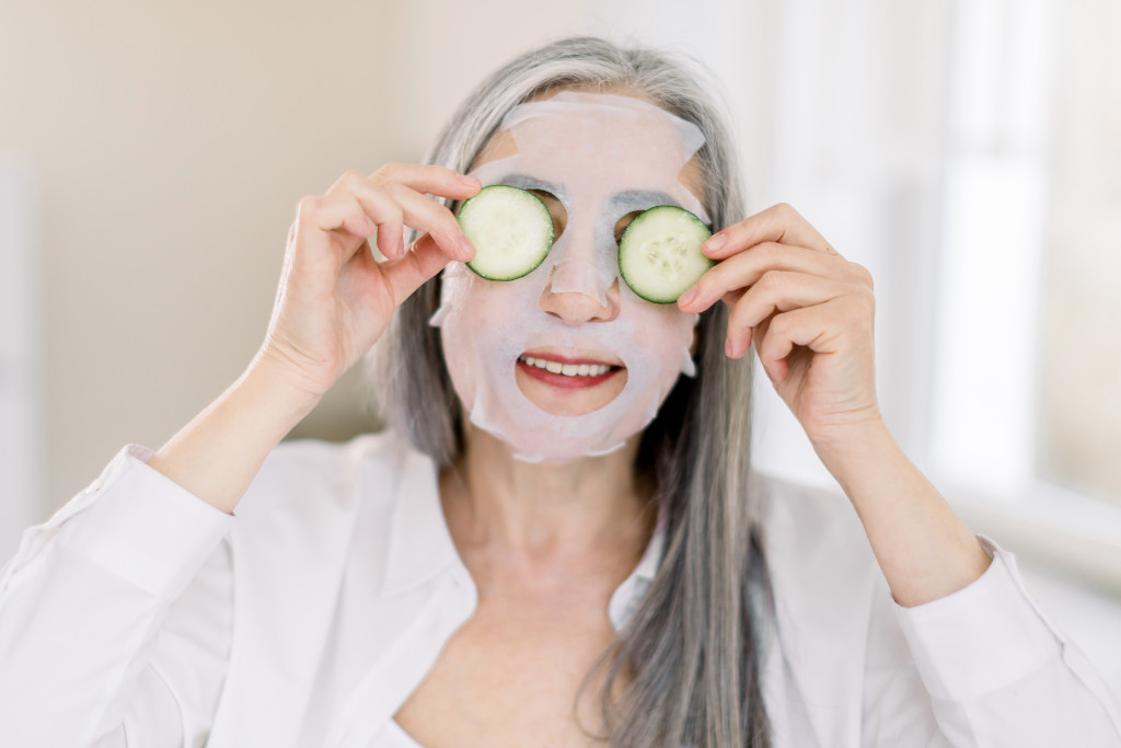 an elderly woman wearing a face mask with cucumbers in her eyes