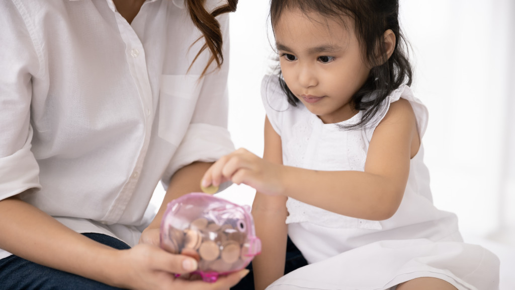 Mother and daughter putting coins in a translucent piggy bank