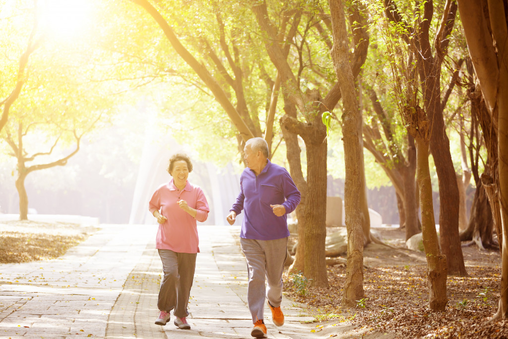 An elderly couple jogging through a park