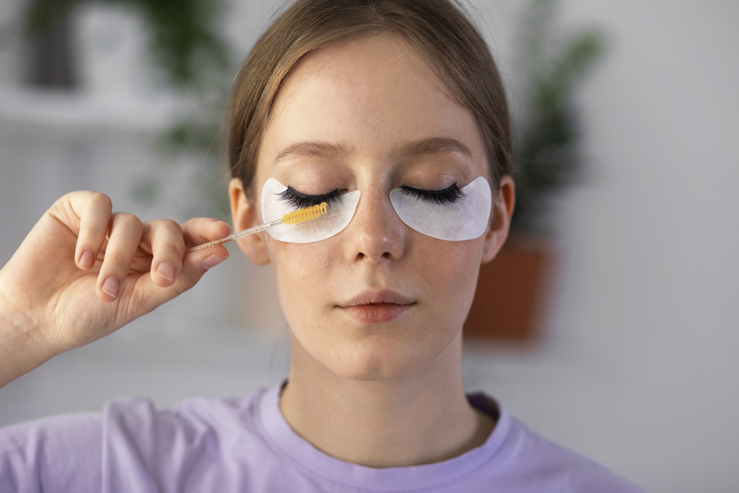 woman removing eyelash extensions using a brush with oil