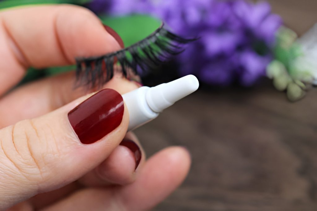 close-up of hand holding eyelash extension and glue
